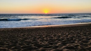 Une plage avec des vagues et un coucher de soleil.