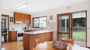 Une cuisine moderne avec des meubles en bois, un îlot central et un coin repas comprenant une table et des chaises.