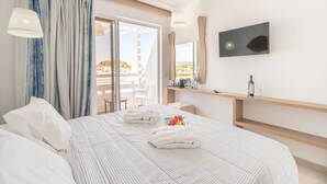 Una habitación de hotel con cama, televisor, escritorio y vistas al exterior.