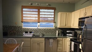 A kitchen with white cabinets, a stainless steel refrigerator, a microwave, and a toaster. - Casa Anonna - Stunning oceans views and pool! (Vieques)