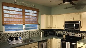 A kitchen with white cabinets, a microwave, a stove, and a dishwasher. - Casa Anonna - Stunning oceans views and pool! (Vieques)
