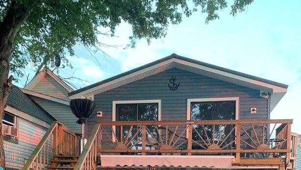 A two-story house with a wooden deck, a covered porch, and a staircase leading to the upper level. - Chautauqua lakefront cottage🐠GREAT LOCATION 🐠Pet friendly (Jamestown)