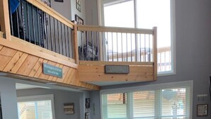 A spacious living room with a high ceiling, a wooden staircase, and a balcony. - Chautauqua lakefront cottage🐠GREAT LOCATION 🐠Pet friendly (Jamestown)