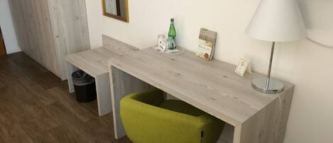 Una habitación moderna con un escritorio de madera, una silla verde, un televisor y una lámpara.