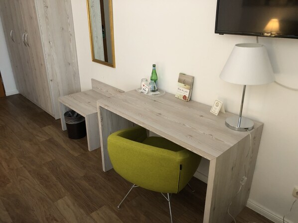 A modern room with a wooden desk, a green chair, a television, and a lamp. - Hotel Residence KG (Bad Segeberg)
