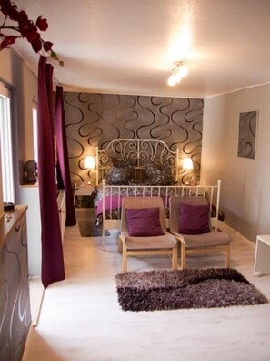 A bedroom with a bed, two chairs, a nightstand, and a decorative wall. - Landhotel Restaurant Wellness Feldmaus (Olzheim)