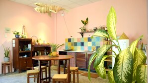 Un rincón comedor acogedor con una mesa y sillas de madera, rodeado de plantas en macetas y electrodomésticos de cocina.