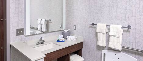A modern bathroom with a white sink, mirror, and towel rack.