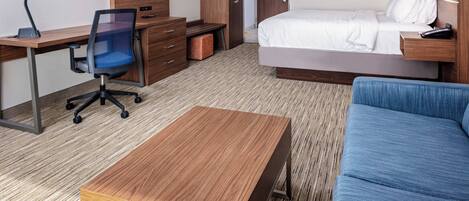 A hotel room with a bed, a desk with a chair, a TV, and artwork on the walls.