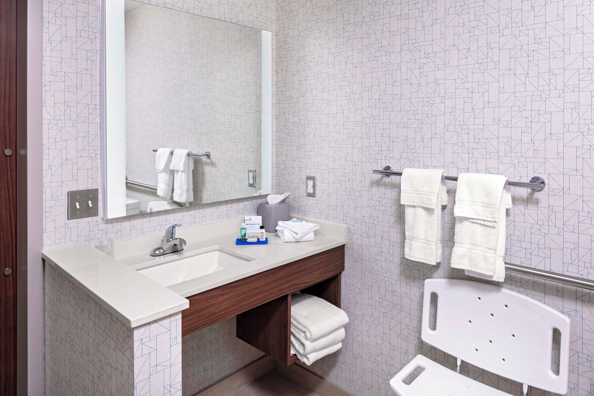A bathroom with a white sink, mirror, and towel rack.