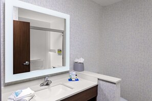 A bathroom with a large mirror, a white sink, a wooden cabinet, and a towel rack. - Holiday Inn Express & Suites Madison by IHG (Madison)