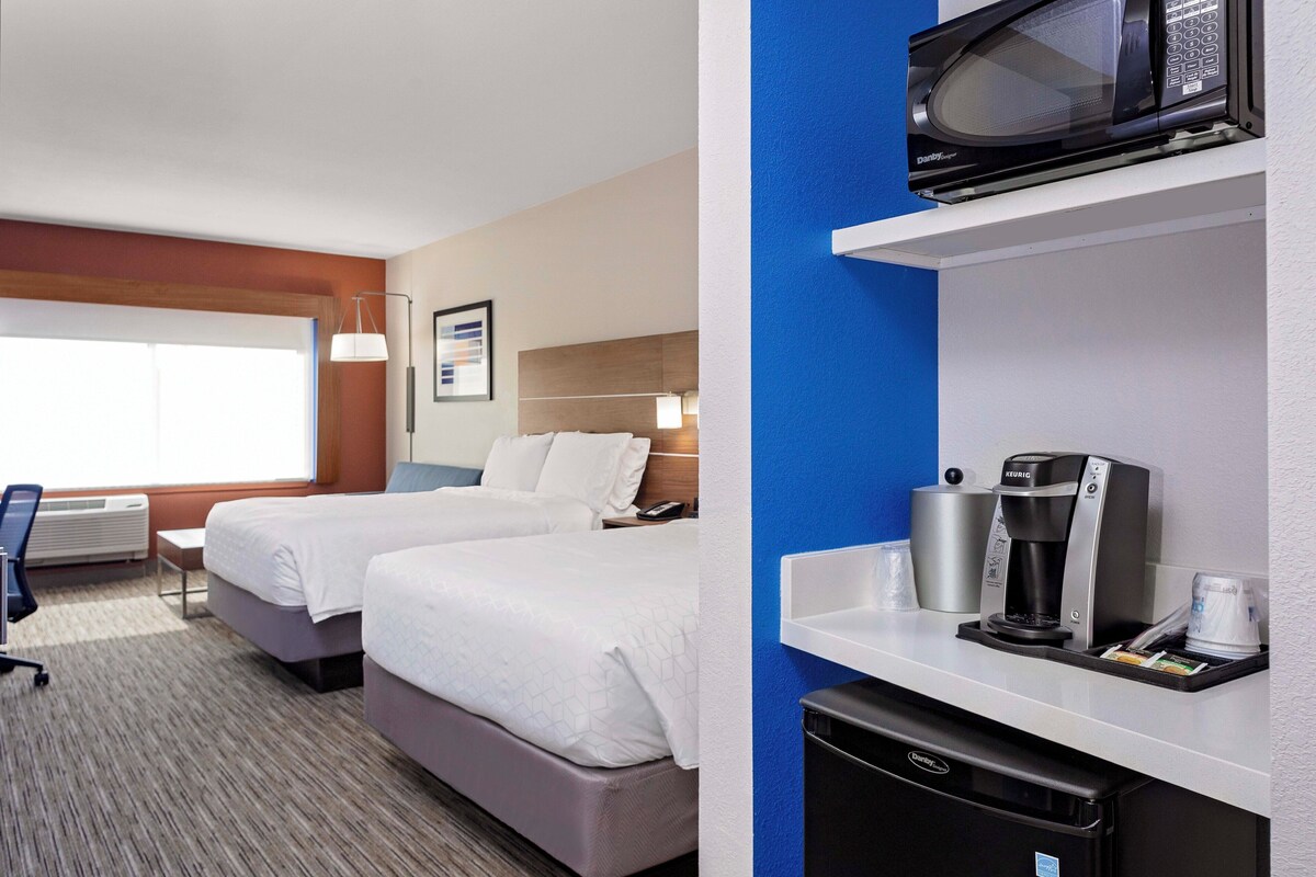 A hotel room with two beds, a microwave, a coffee maker, and a small refrigerator.