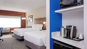 A hotel room with two beds, a microwave, a coffee maker, and a small refrigerator.