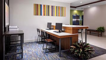 A reception desk with two computer monitors, a printer, and a seating area with chairs.