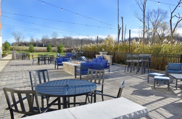 An outdoor patio area with tables and chairs, a fire pit, and string lights. - Holiday Inn Express & Suites Madison by IHG (Madison)