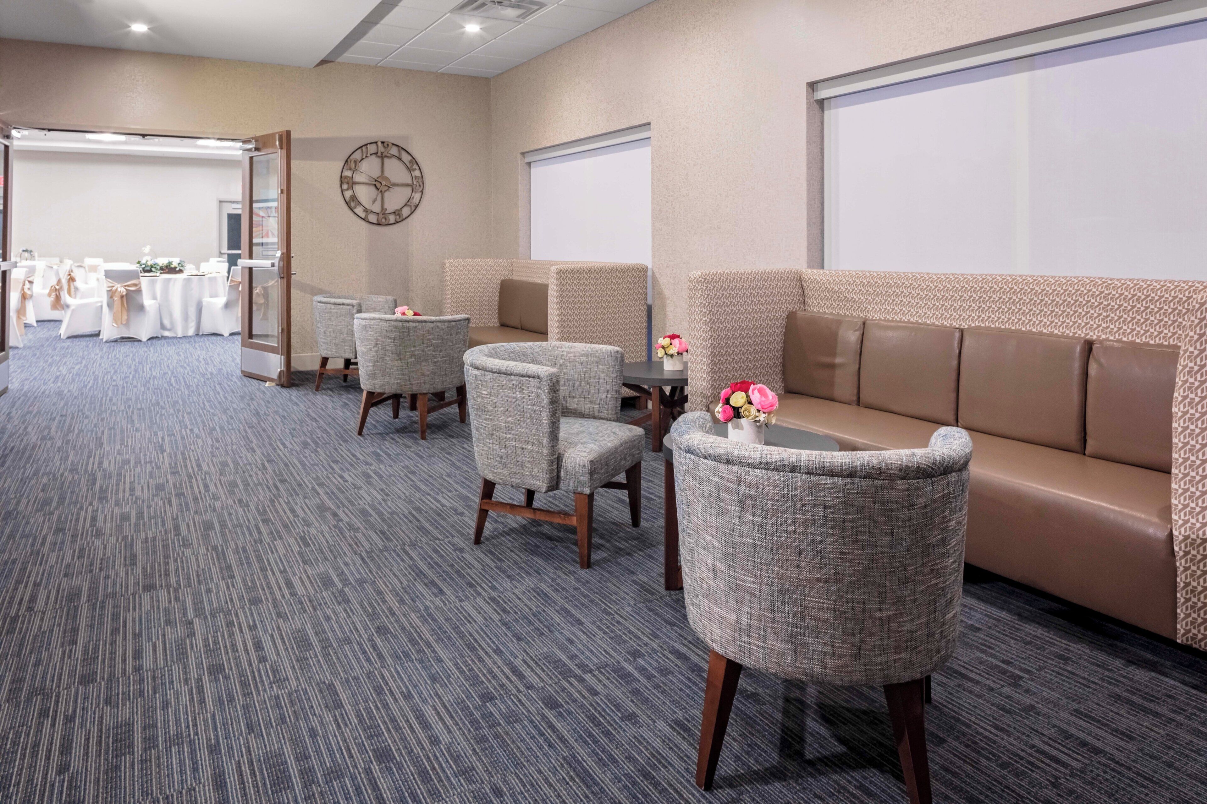A conference room with a carpeted floor, a sofa, and two chairs.