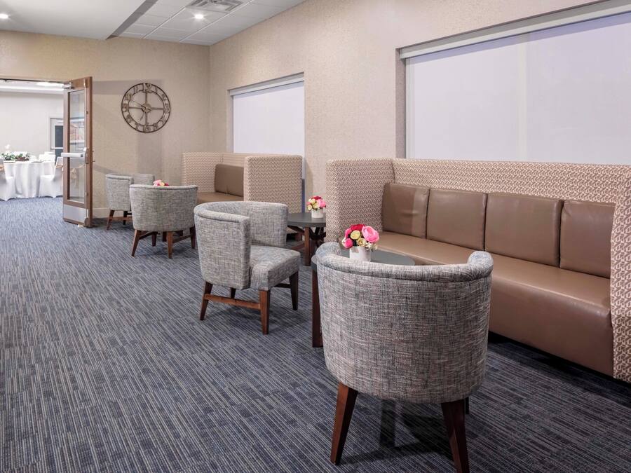A conference room with a carpeted floor, a sofa, and two chairs.