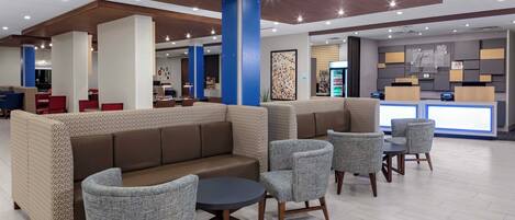 A modern lounge area with sofas, armchairs, and a reception desk.