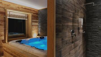 Interior de una cabaña de madera con jacuzzi, ventana y zona de ducha.