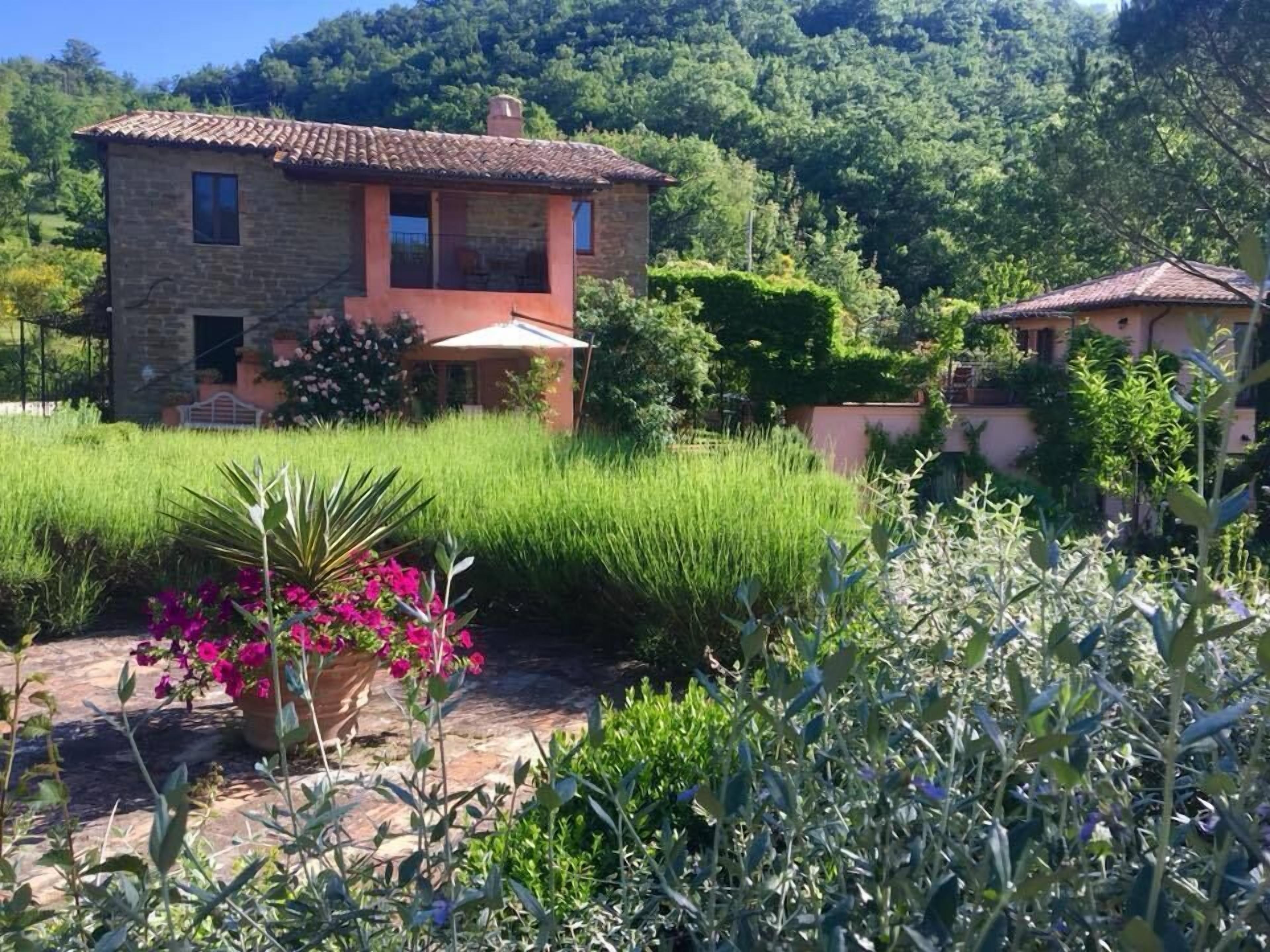 A stone house with a tiled roof, surrounded by lush greenery and a well-maintained garden.