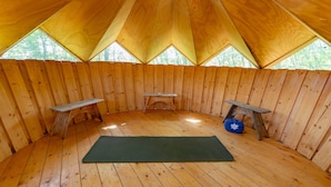 A tent with a wooden interior, two benches, and a yoga mat. - Casa Rosa (Assisi)