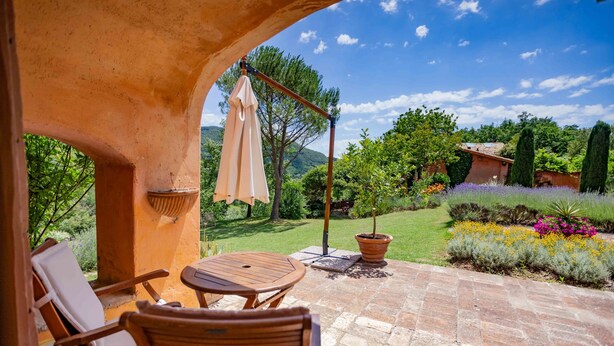 An outdoor patio with a wooden table and chairs, a hanging umbrella, and a potted plant. - Casa Rosa (Assisi)