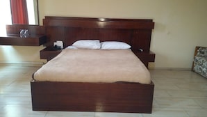 Een groot bed met een houten hoofdeinde, een nachtkastje en een spiegel.