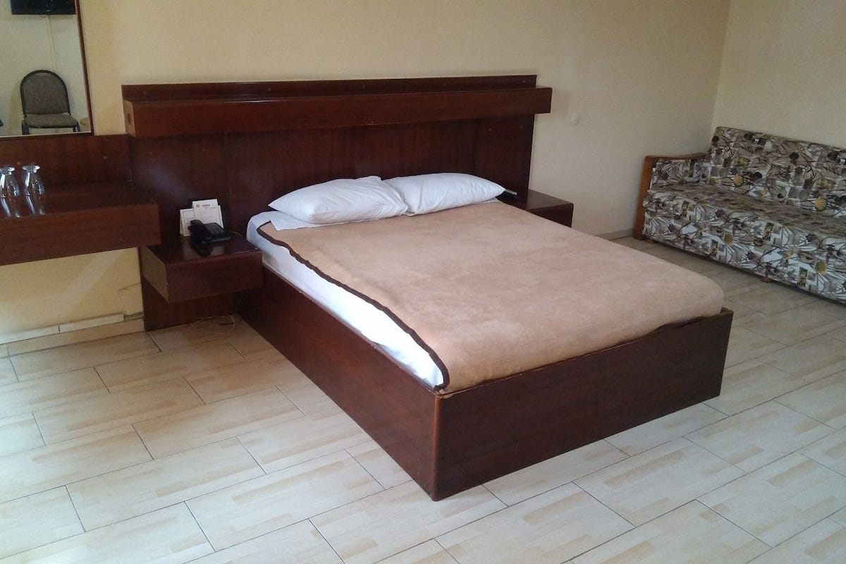 Una camera da letto con un letto in legno, un comodino, una poltrona e uno specchio.