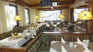 Ein Restaurant mit Holzvertäfelung, mehreren Tischen und Pendelleuchten.