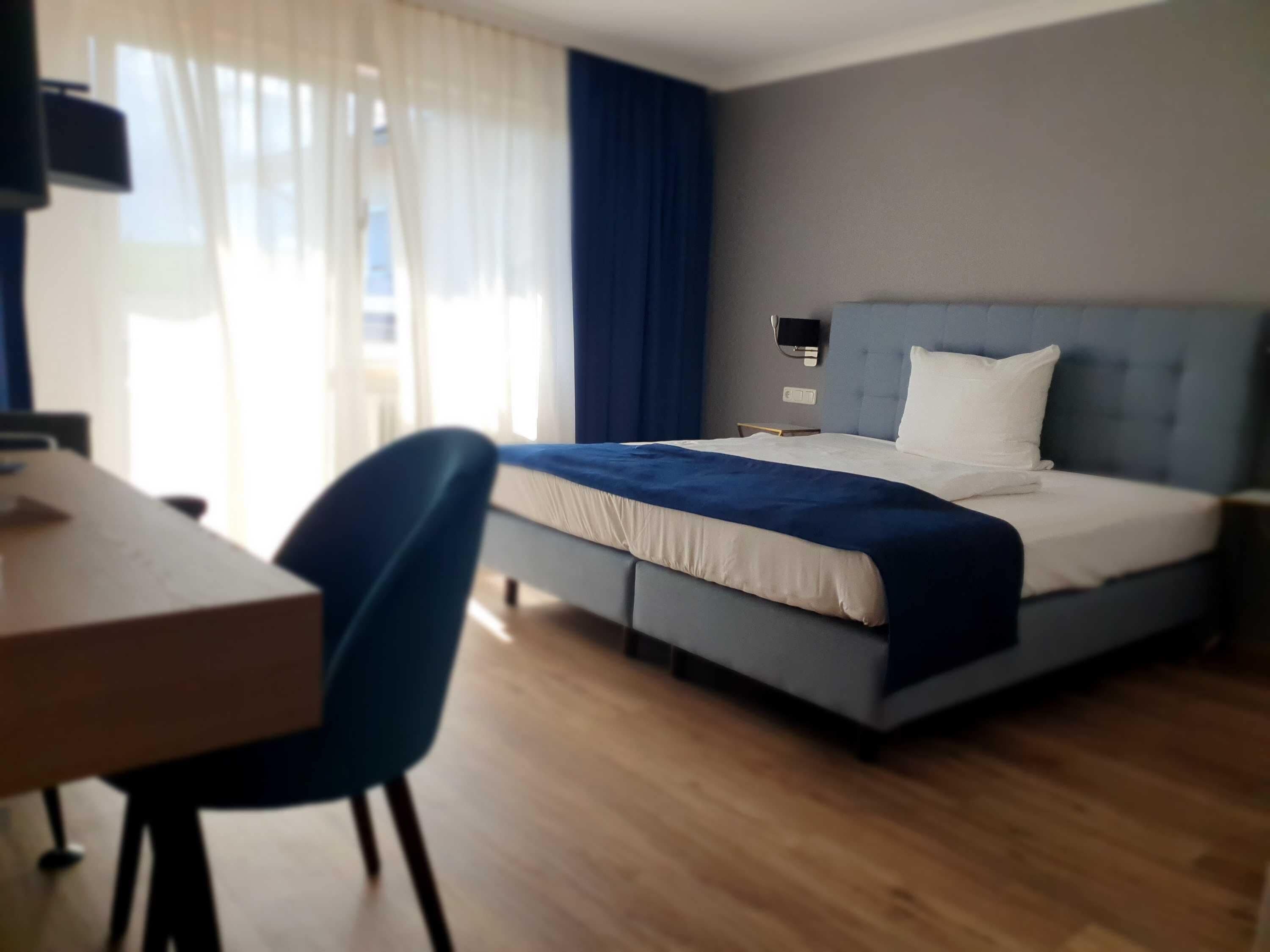 A hotel room with a bed, a desk, and a chair.