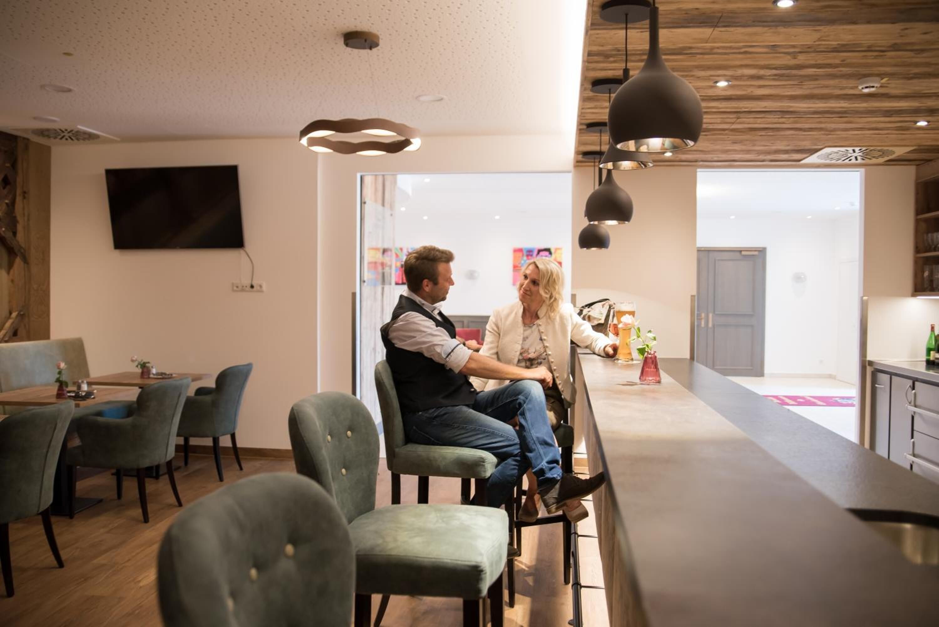 A modern interior with a bar area, seating, and a TV mounted on the wall.