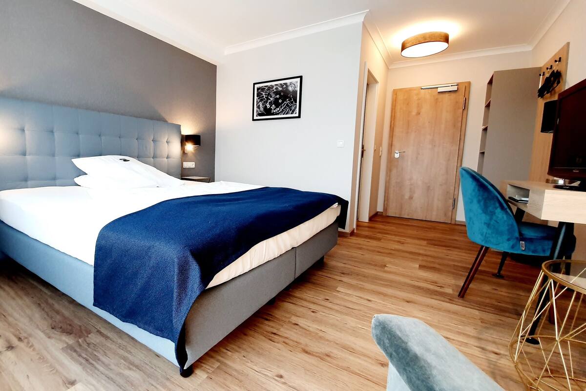 A modern hotel room with a large bed, bedside tables, a desk, and a chair.