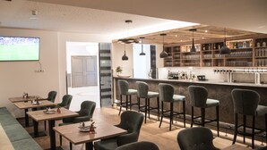 A modern bar area with wooden shelves, bar stools, and a television displaying a sports game.