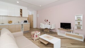 A modern living room with a sofa, a coffee table, a TV, a dining area with chairs, and a kitchen area with cabinets and appliances. - Apartments Marmo (Zupa dubrovacka)