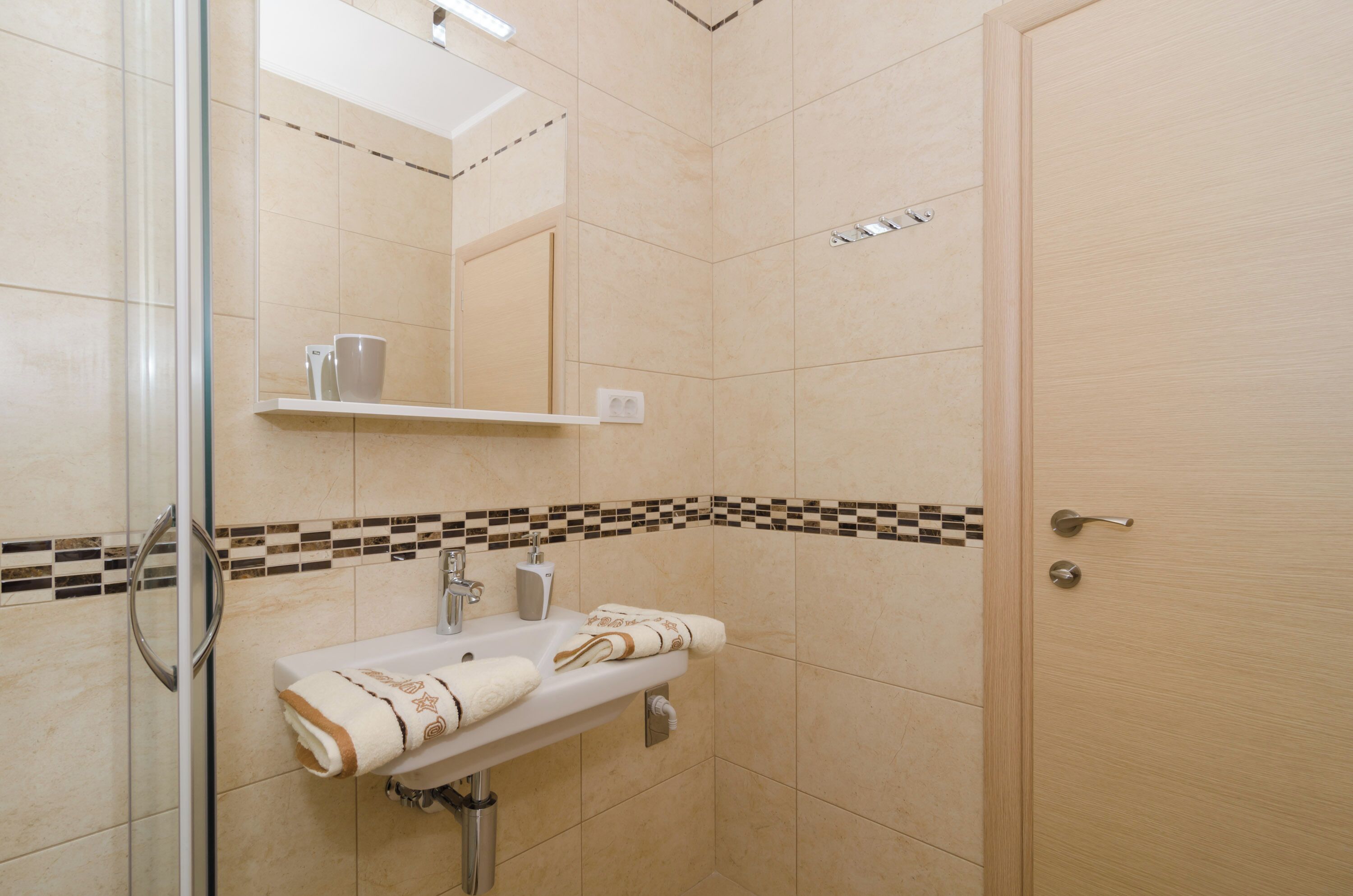 A bathroom with a glass shower door, a sink with a towel rack, and a mirror above the sink.
