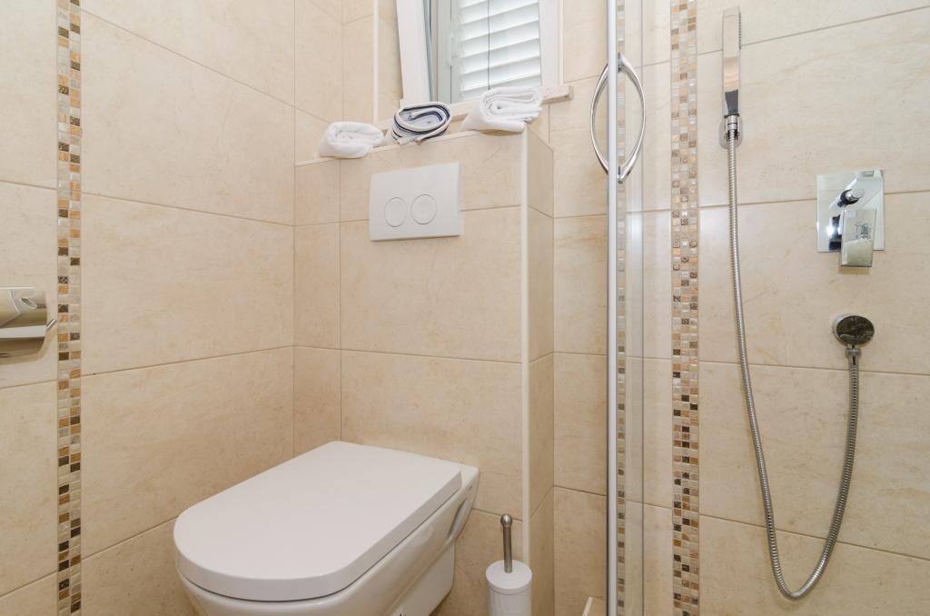 Ein kleines, modernes Badezimmer mit Toilette, Dusche und Handtuchhalter.