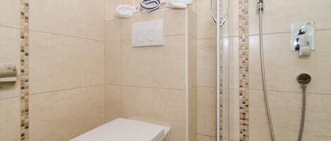 Ein kleines, modernes Badezimmer mit Toilette, Dusche und Handtuchhalter.