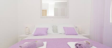 A hotel room with a large bed, two nightstands, a mirror, and a window with curtains.