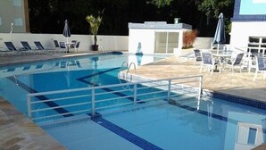 Una piscina con acqua cristallina, bordo piastrellato e sdraio.