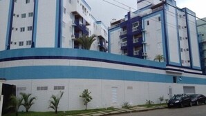 Un edificio residenziale a più piani con una combinazione di colori blu e bianco, con balconi e un ingresso chiuso da cancello.