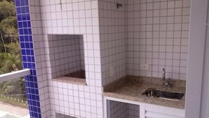Una piccola cucina con piastrelle bianche, un lavello e una finestra che si affaccia sul verde.