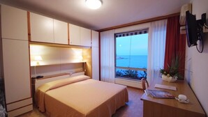 A hotel room with a bed, a desk, a chair, a window with a view, and a TV on the wall. - Hotel La Stella (Campo nell'Elba)