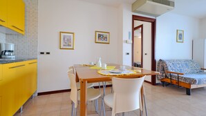 Un espacio habitable compacto con zona de comedor, kitchenette y sofá cama.