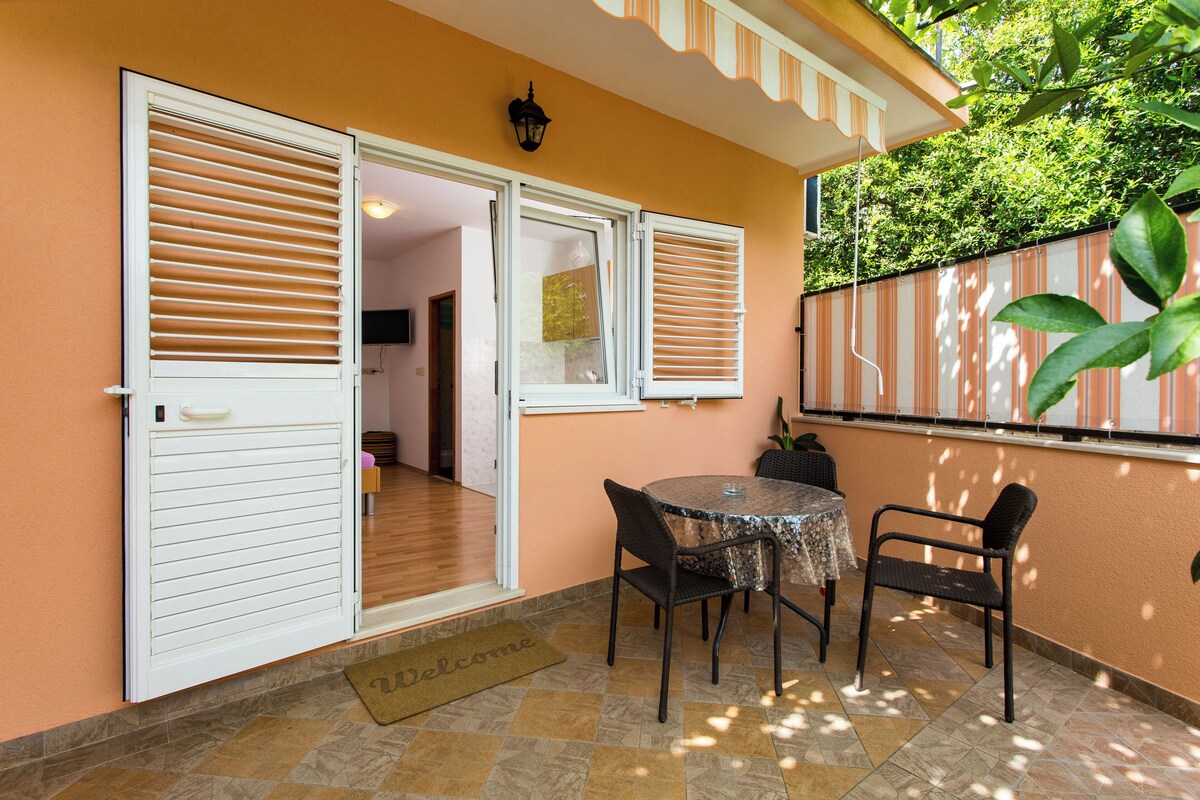A patio area with a table and chairs, a door, and a welcome mat.