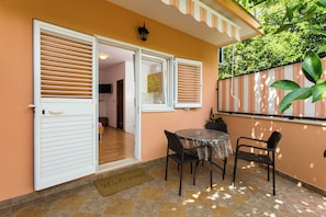 A patio area with a table and chairs, a door, and a welcome mat. - Apartments Bibijana (Zupa dubrovacka)