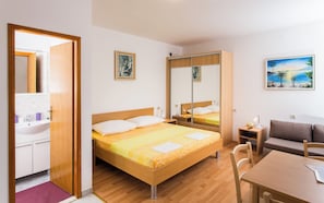 A hotel room with a wooden bed, a desk, a chair, a mirror, and a painting on the wall. - Apartments Bibijana (Zupa dubrovacka)