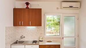 A compact kitchen with a sink, stove, and white cabinets. - Apartments Bibijana (Zupa dubrovacka)