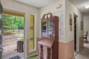 A hallway with a wooden cabinet, a door leading outside, and a wall with informational posters.