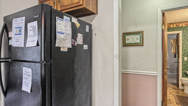 A black refrigerator with various papers and notices attached to it.
