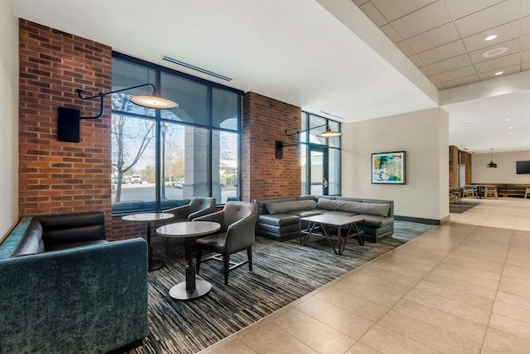A modern lounge area with brick walls, large windows, and contemporary furniture. - Hyatt Place Florence Downtown (Florence)